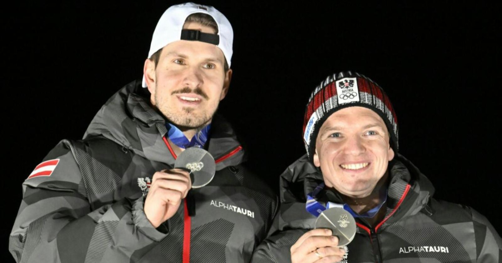 Die Rodler Steu und Kindl posieren in Teamjacken mit ihren Silbermedaillen bei den Olympischen Spielen in Cortina d’Ampezzo.