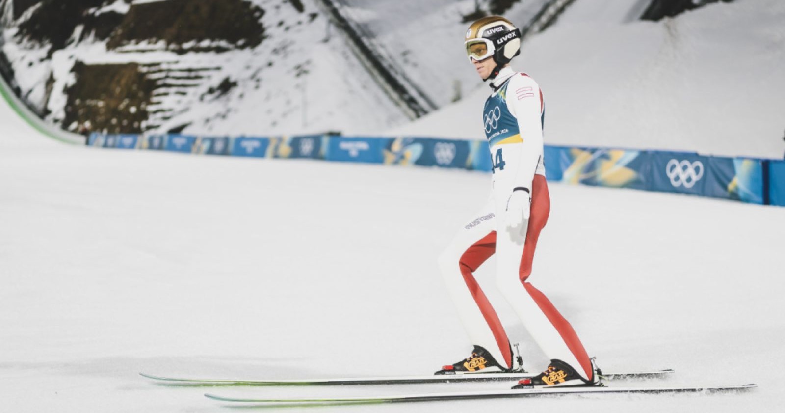 Skispringer Jan Hörl steht nach einem Sprung bei den Olympischen Spielen in Predazzo im Auslauf der Großschanze im Schnee.