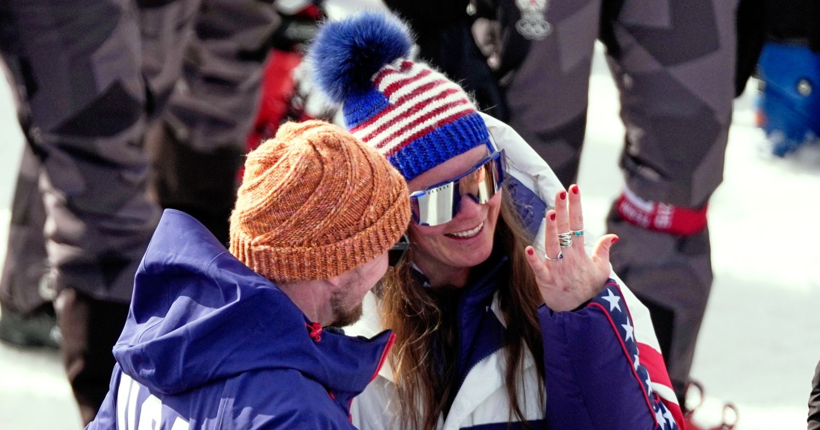 Breezy Johnson lächelt im Olympia-Zielbereich und hält ihren Verlobungsring in die Kamera, während ihr Freund Connor Watkins neben ihr steht.
