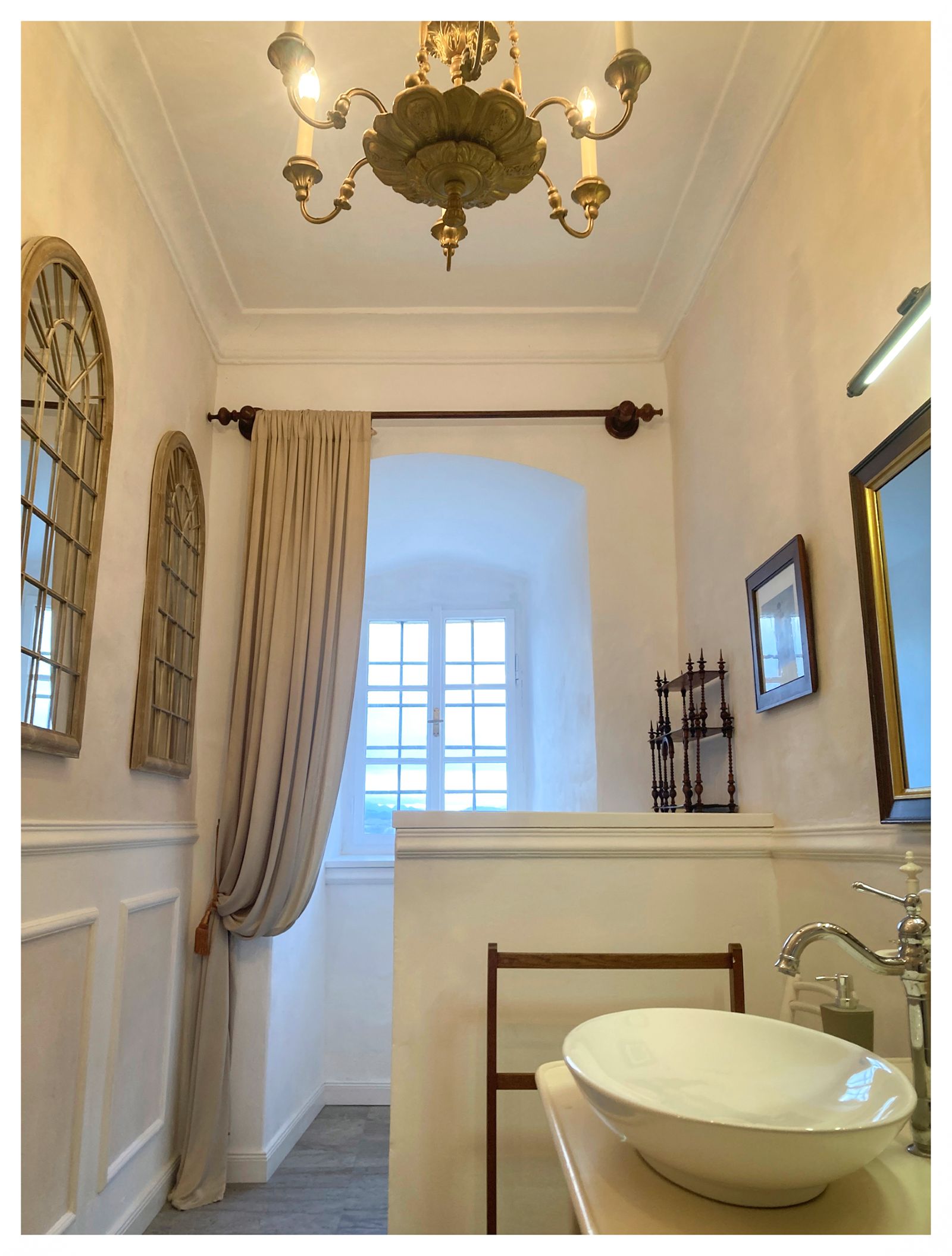 Historisch gestaltetes Badezimmer in Burg Clam mit freistehendem Waschbecken, Kronleuchter und hohen Fenstern.