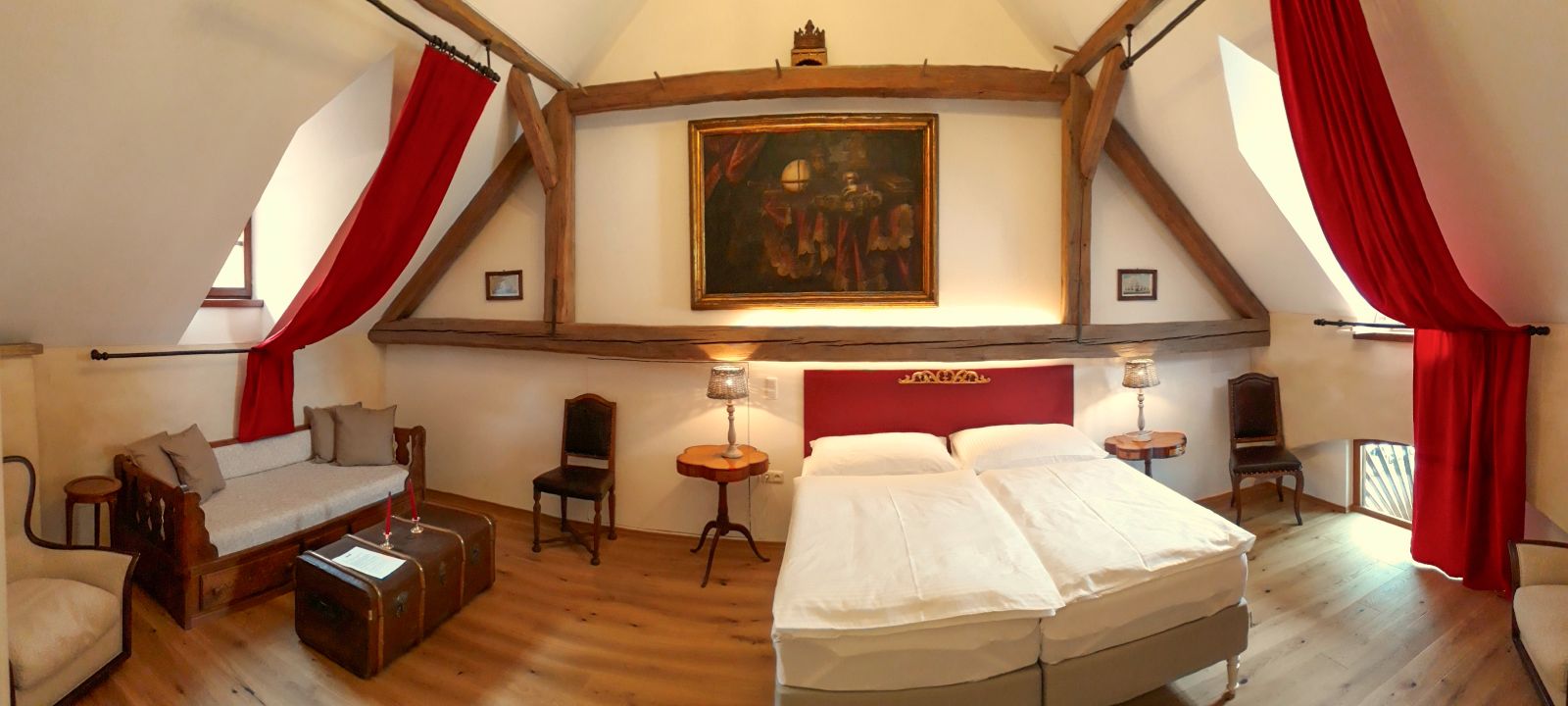 Schlafzimmer in Burg Clam mit Holzbalken, roten Vorhängen und Doppelbett in historischem Ambiente.