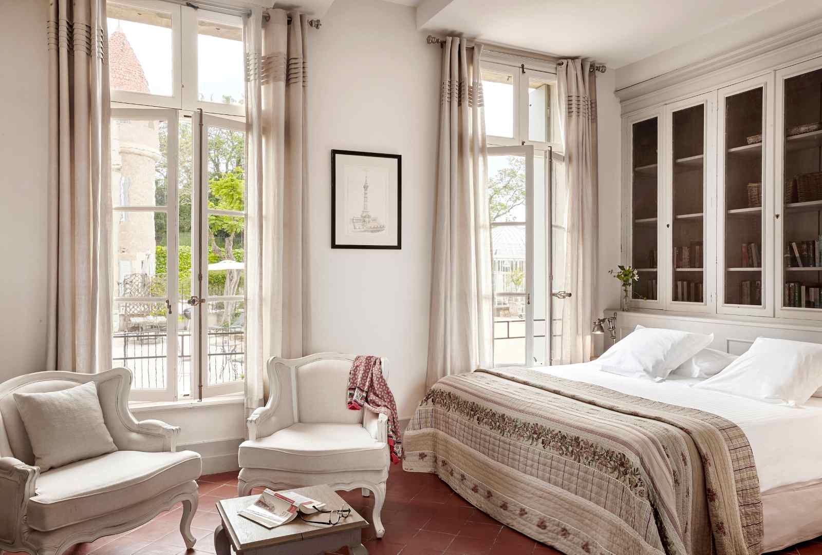 Helles Gästezimmer im Château Les Carrasses mit französischen Fenstern, klassischem Mobiliar und Blick ins Grüne.
