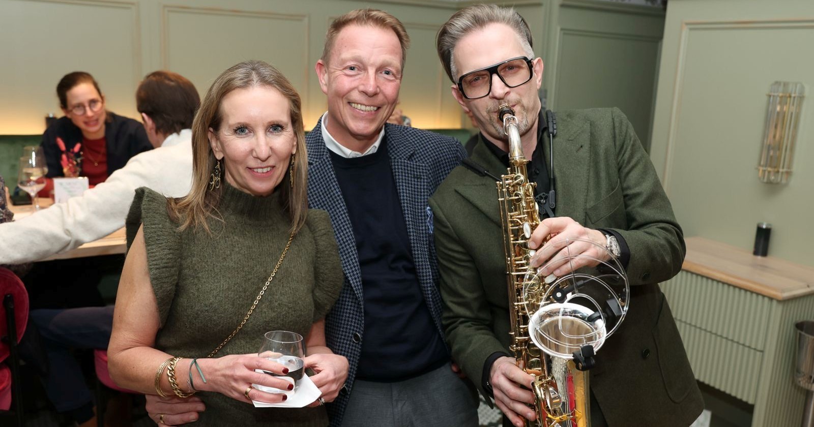 Frau  mit Wasserglas, Mann im karierten Sakko und ein Saxophonist