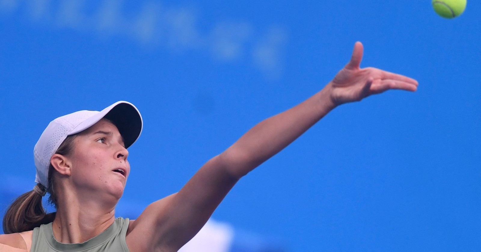 Lilli Tagger serviert konzentriert während eines Tennismatches beim WTA-Turnier in Mumbai vor blauem Hintergrund.