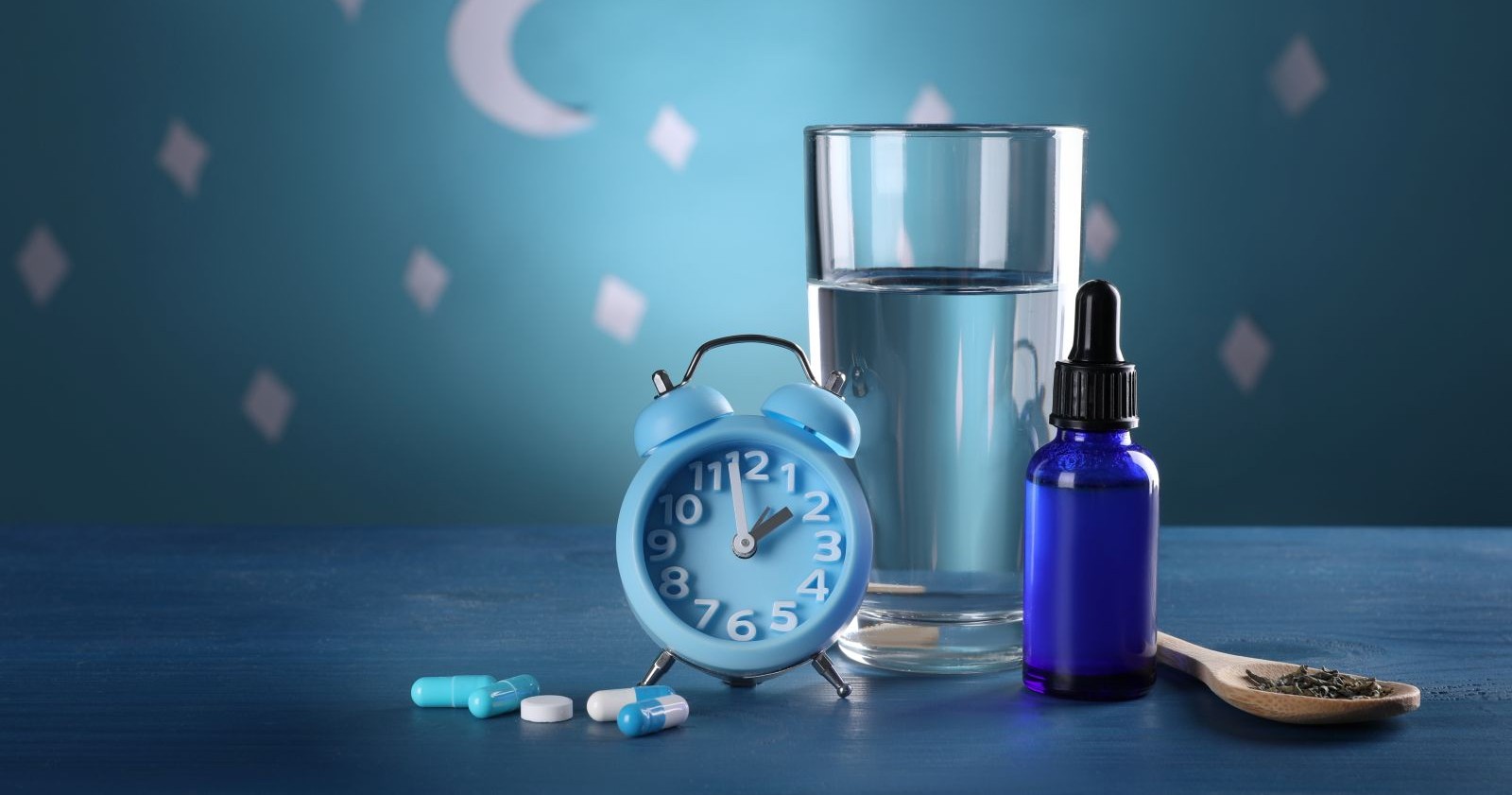 Ein blauer Wecker, ein Glas Wasser und Medikamente.