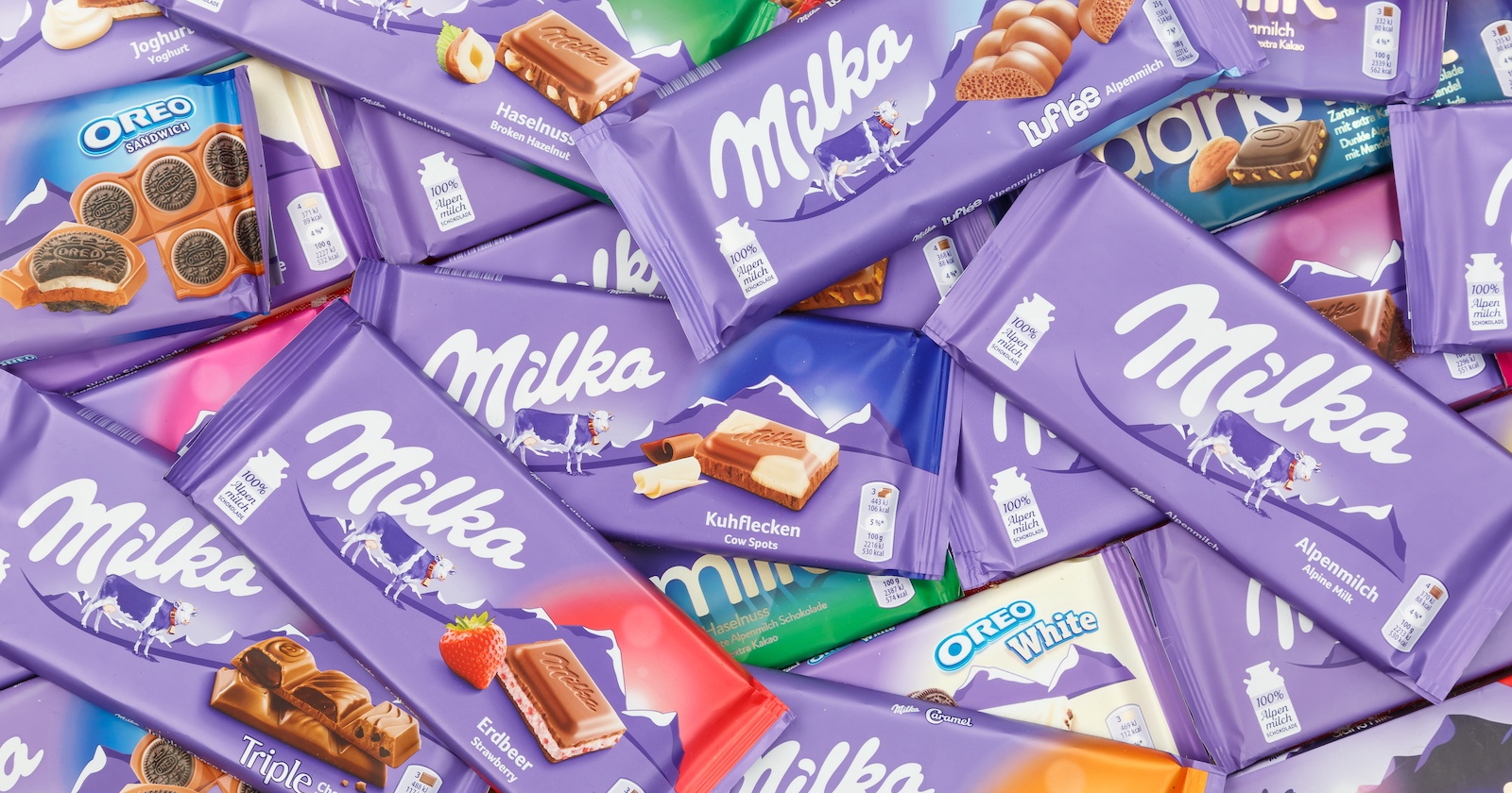 Mehrere Milka-Schokoladentafeln in lila Verpackung, darunter Alpenmilch, Oreo und Haselnuss – Symbolbild zur Milka-Schokolade und ihrer Preiserhöhung.