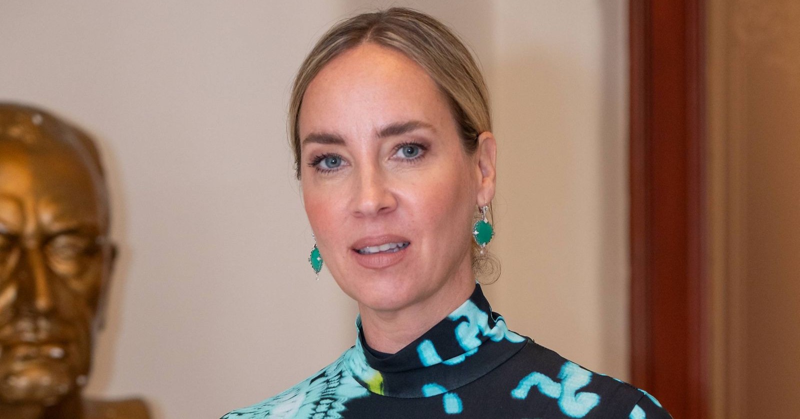 Beziehung und Tinder/ Nadja Bernhard mit hochgesteckten Haaren und grünen Ohrringen vor einer hellen Wand/ Nadja bernhard spricht über