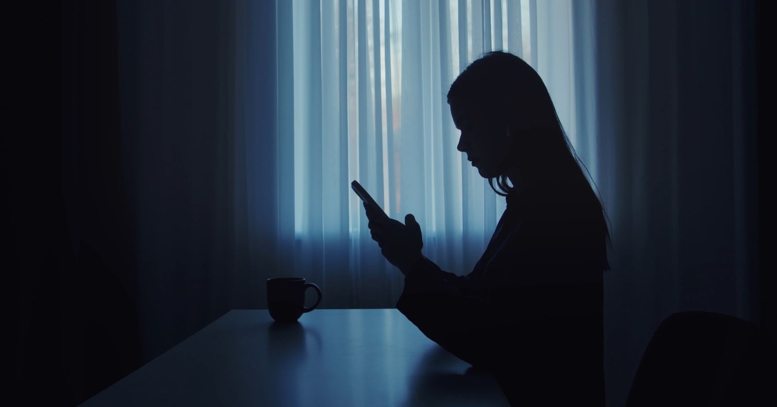 Frau im Dunkeln am Telefon/ Frau in Brandenburg blockiert Notruf durch Telefonterror