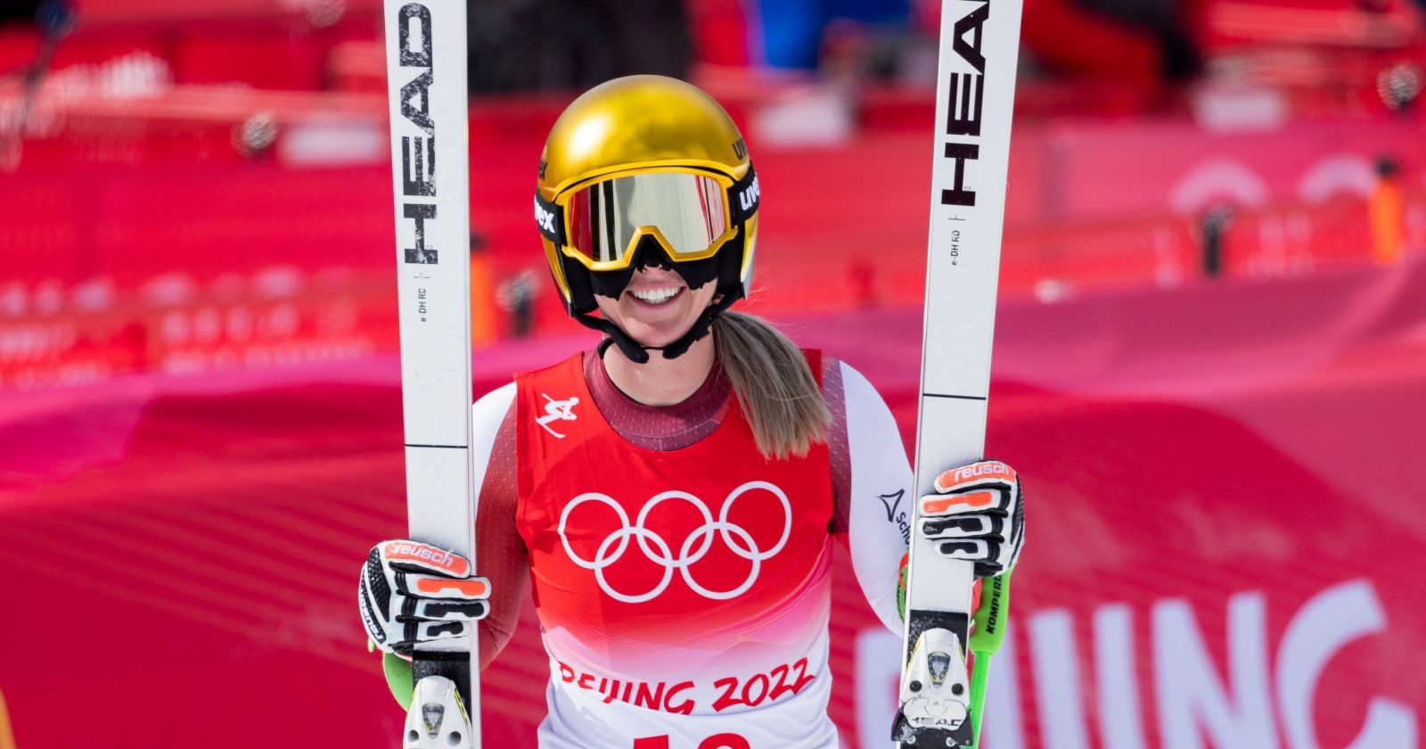 Cornelia Hütter mit goldenem Helm und Skiern im Olympia-Dress, bereit für den Super-G der Olympischen Winterspiele 2026 in Bormio.