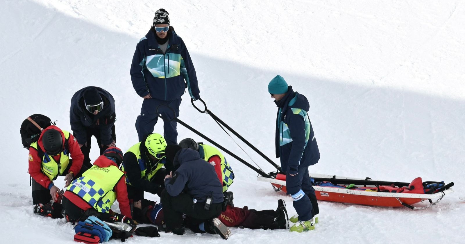Mehrere Sanitäter und Helfer leisten auf der Schneepiste Erste Hilfe für Liu Jiayu nach ihrem Sturz in der Halfpipe bei den Olympischen Winterspielen 2026; im Hintergrund steht ein Rettungsschlitten bereit.