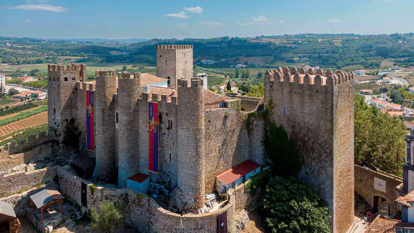 Mittelalterliche Burg von Óbidos in Portugal mit Zinnen, Türmen und dicken Steinmauern, gelegen auf einer Anhöhe mit Blick auf die umliegende Landschaft.