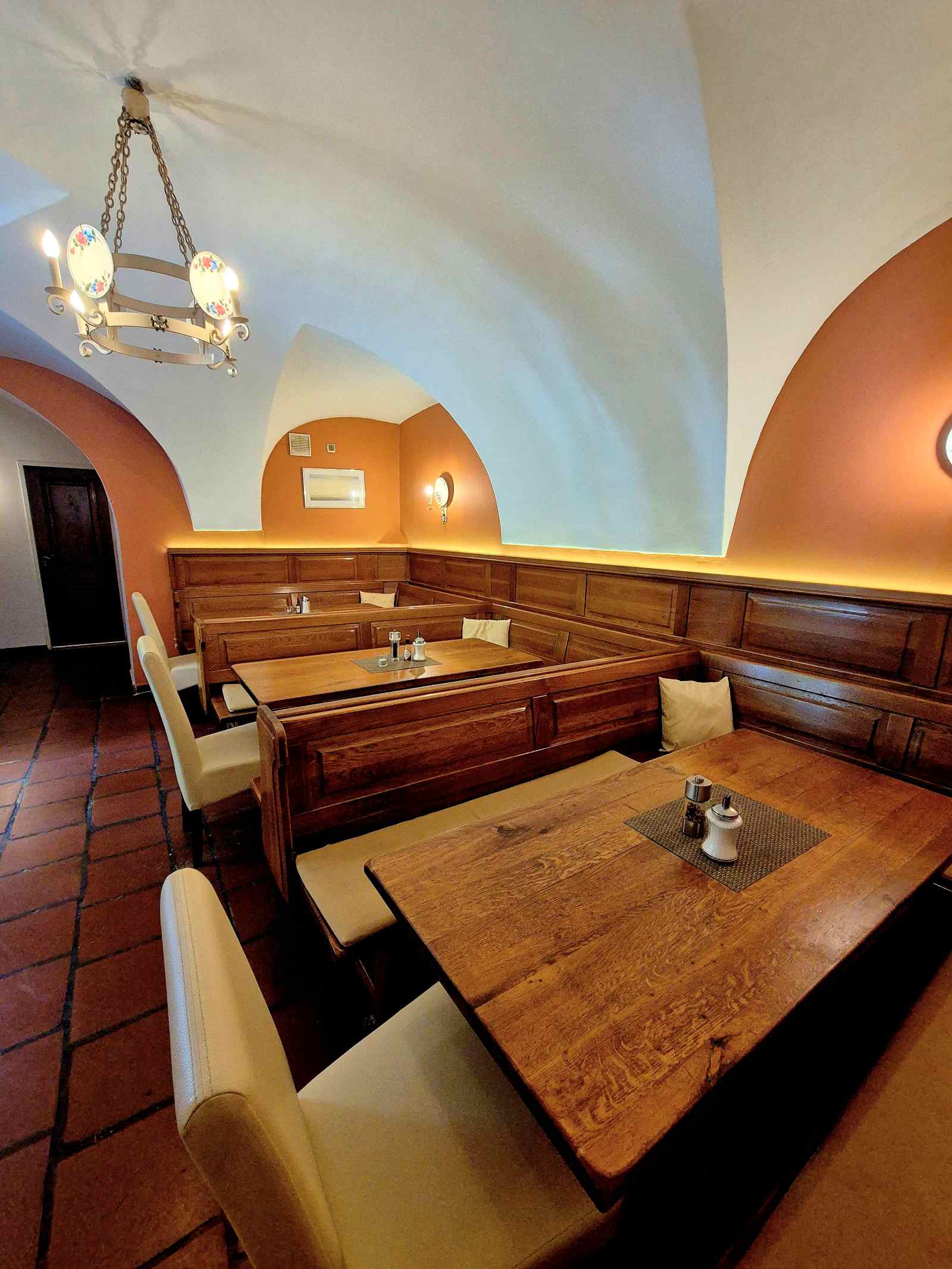 Gewölberaum im Hotel Knappenstöckl mit Holztischen, Sitzbänken und warmem Licht.