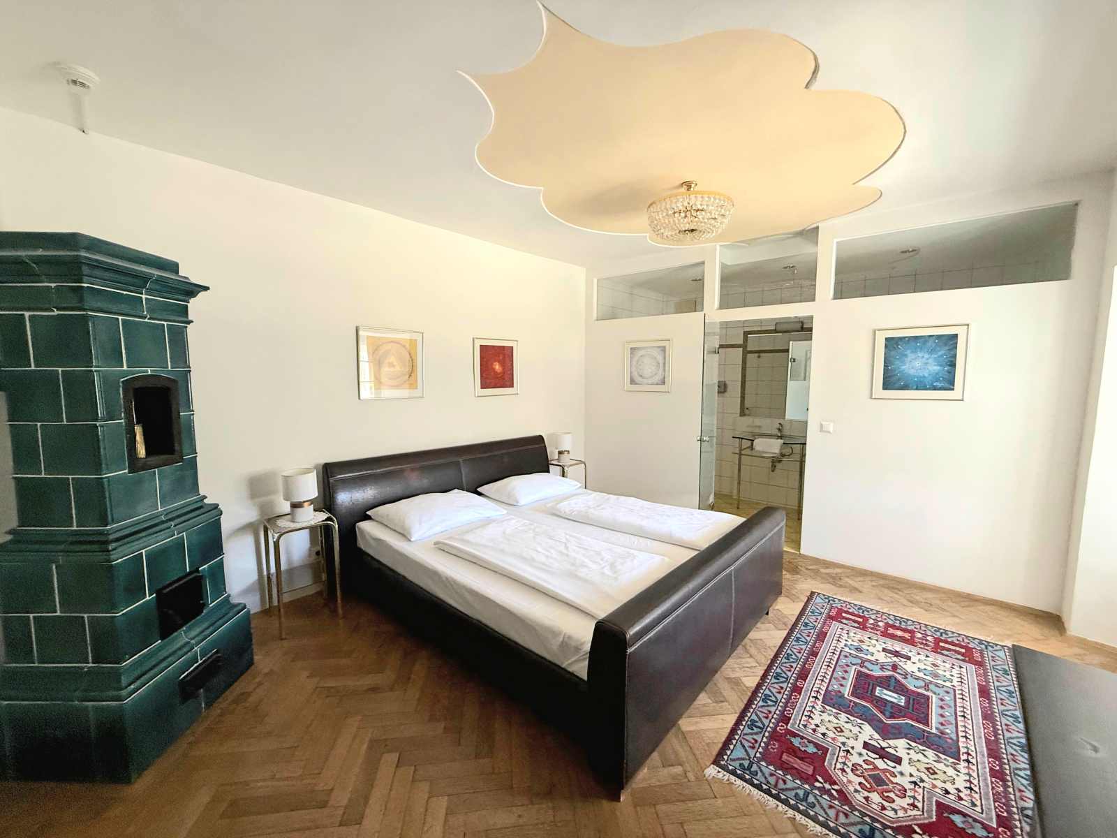 Modern eingerichtetes Gästezimmer im Hotel Knappenstöckl mit Doppelbett, Kachelofen und Parkettboden.