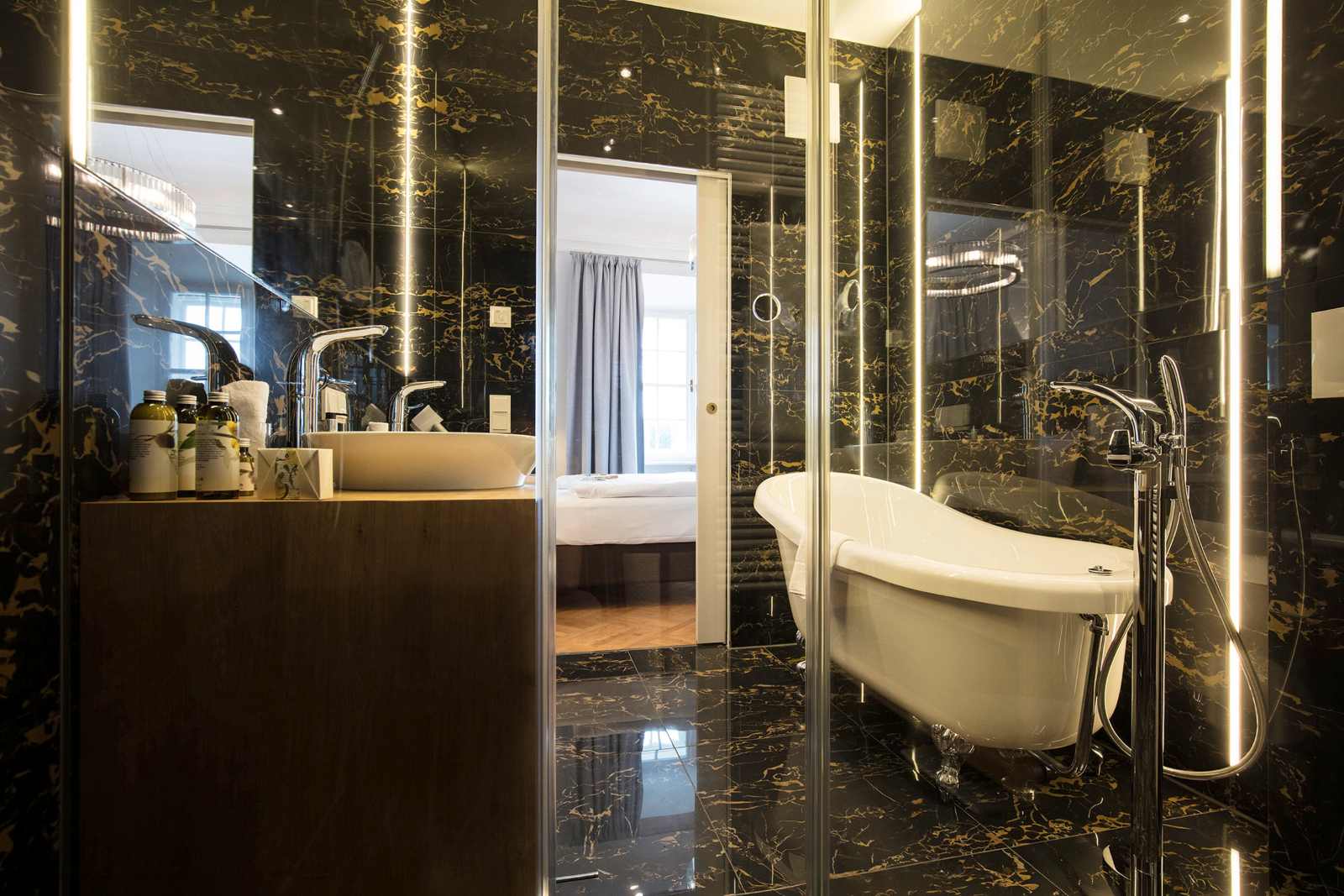 Modern ausgestattetes Badezimmer in Schloss Leopoldskron mit freistehender Badewanne und dunklen Marmorelementen.