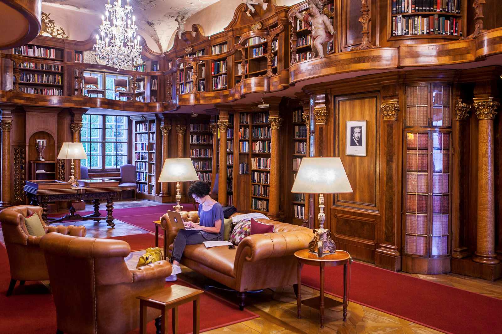Prunkvolle Bibliothek mit Holzvertäfelung, Galerie und Kronleuchter im Schloss Leopoldskron.