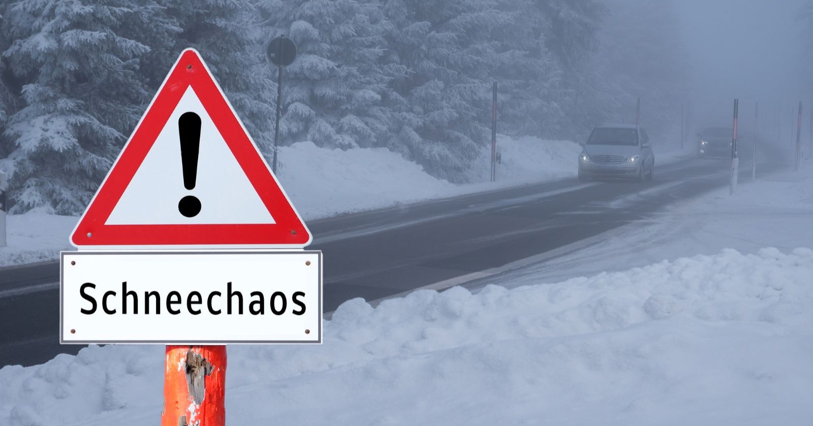 Warnschild „Schneechaos“ an schneebedeckter Landstraße mit Autos bei winterlichen Straßenverhältnissen – Schnee sorgt in Österreich für Probleme im Verkehr und bei der Stromversorgung.