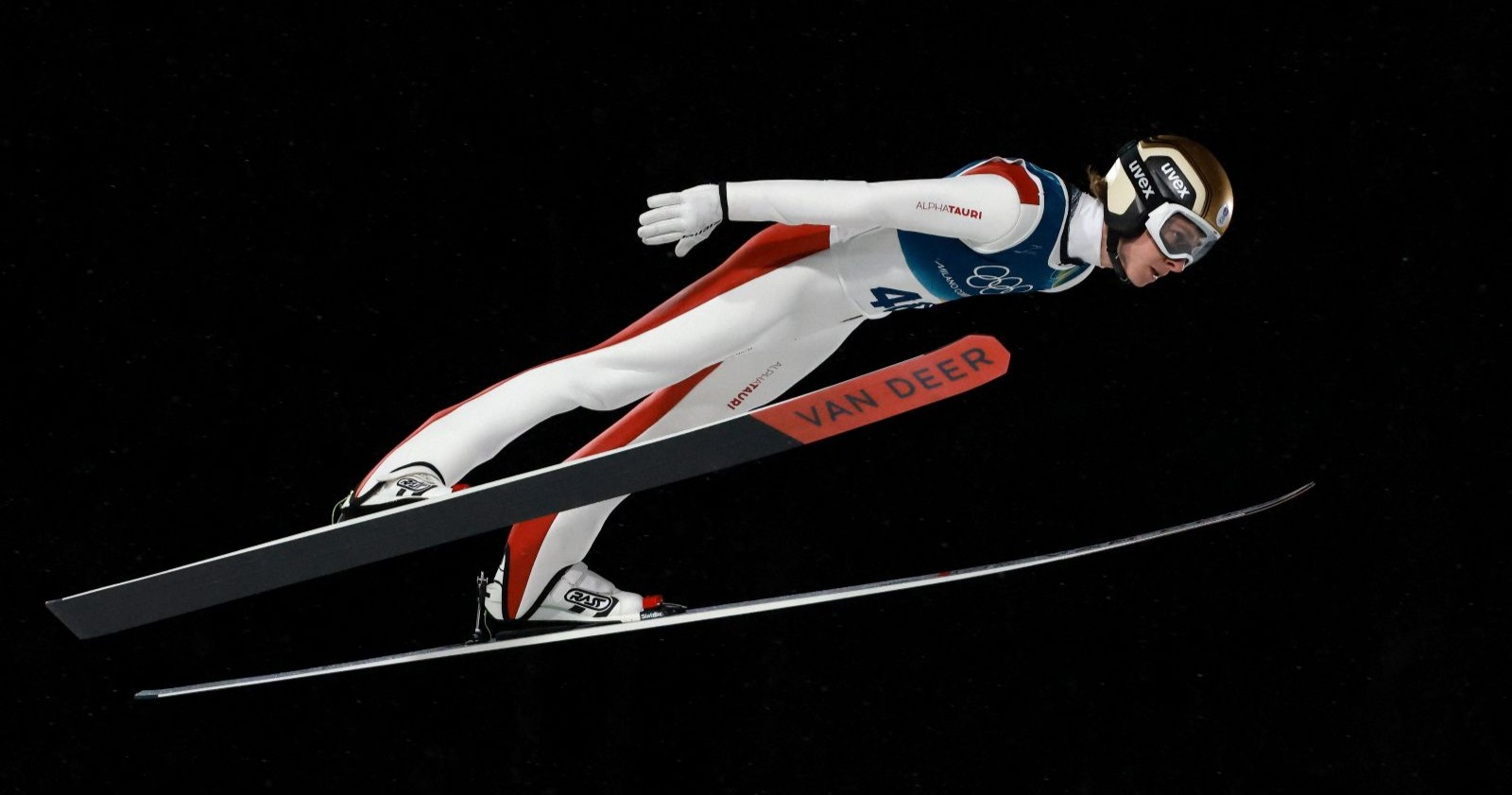 Österreichischer Skispringer im Flug bei den Olympischen Winterspielen 2026 auf der Großschanze in Val di Fiemme.