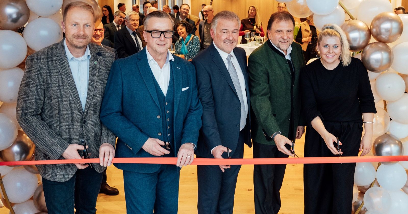 Vier Männer und eine Frau schneiden ein Band durch