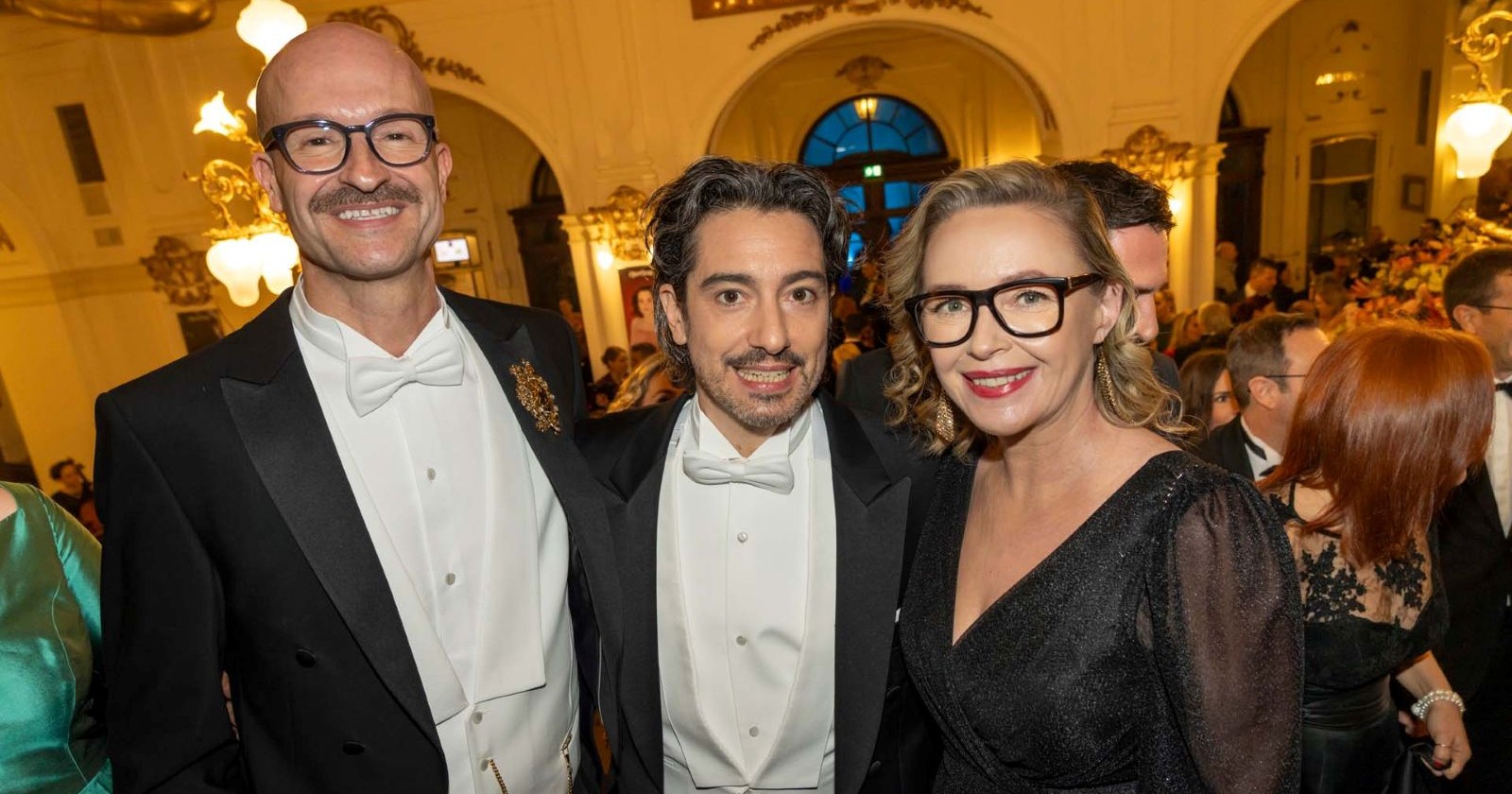 Zwei Männer und eine Frau lachen in die Kamera