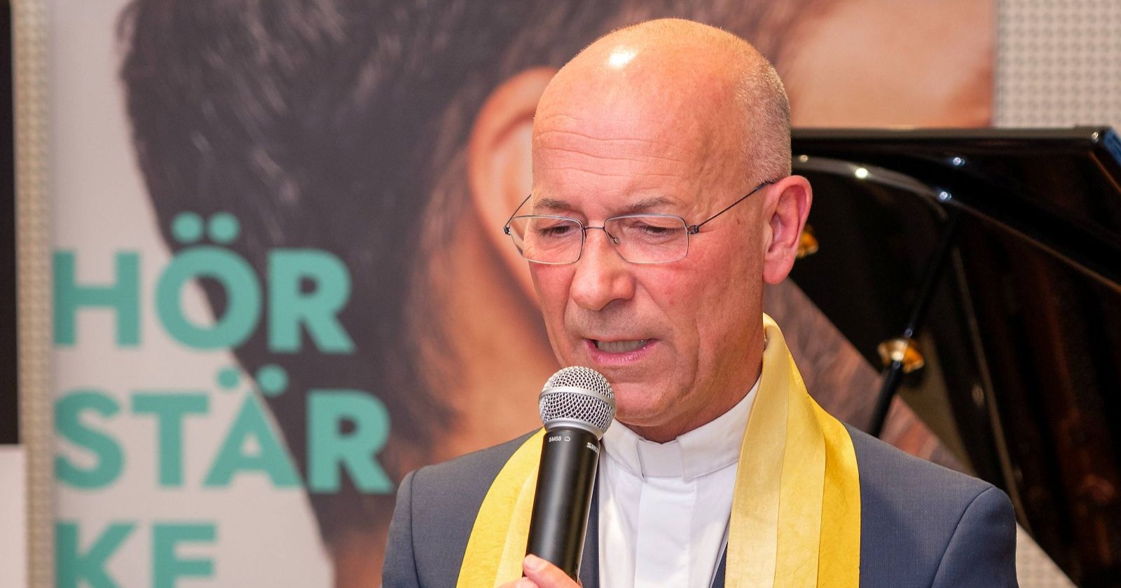 Dompfarrer Toni Faber mit Mikrophon in der Hand/ Dompfarrer Toni Faber spricht über seine Schock-Diagnose in der Jugend.