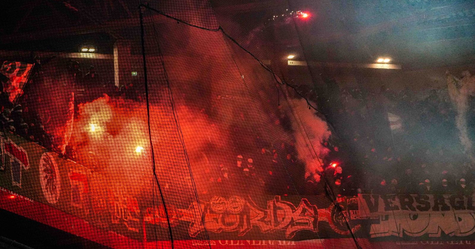 Brennende Pyrotechnik im Gästesektor während des 348. Wiener Derbys; Polizisten stehen vor der Fantribüne des SK Rapid