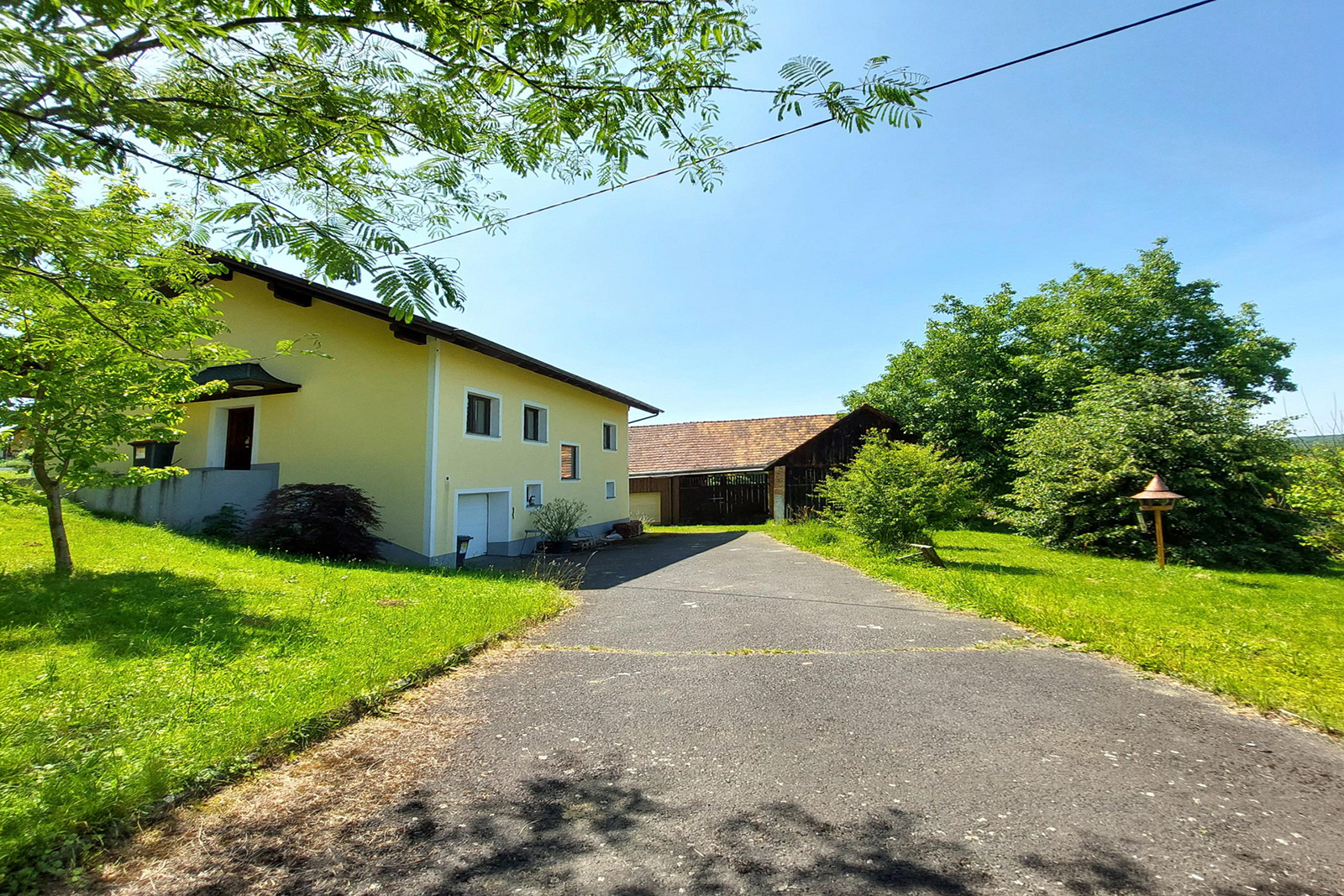 Haus mit gelber Fassade im Grünen | Credit: REMAX
