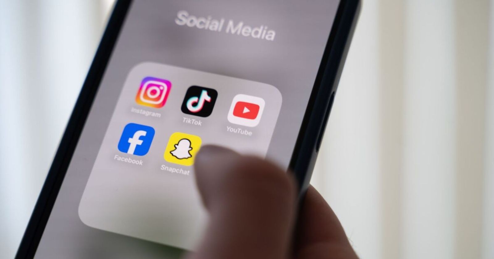 Smartphone mit Social-Media-Apps wie Instagram, TikTok, YouTube, Facebook und Snapchat – Symbolbild für Social-Media-Verbot unter 14 Jahren