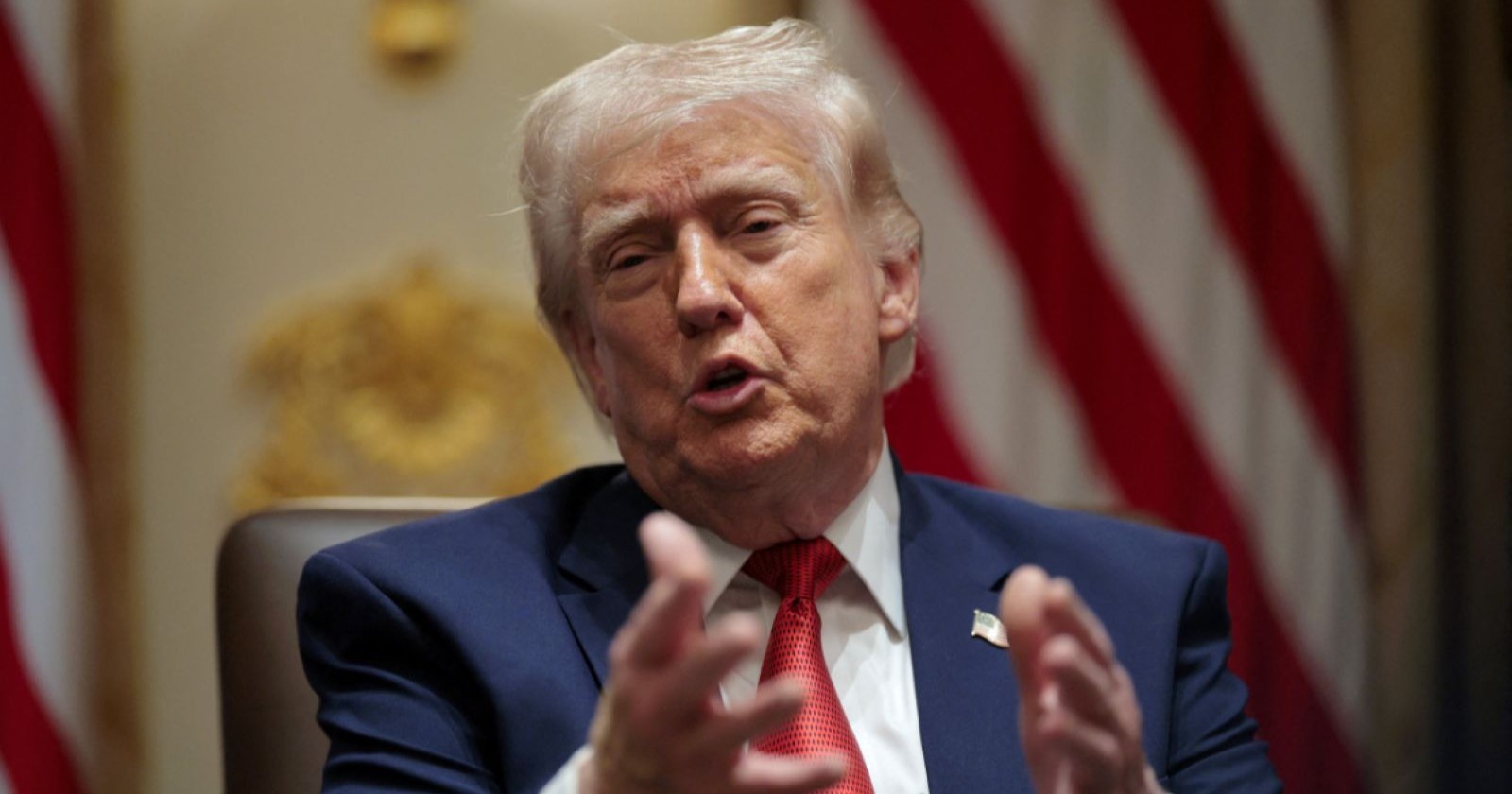 Donald Trump spricht gestikulierend während eines Interviews vor einer US-Flagge im Hintergrund/ Er gratuliert IOC zu Olympia-Bann für Transfrauen