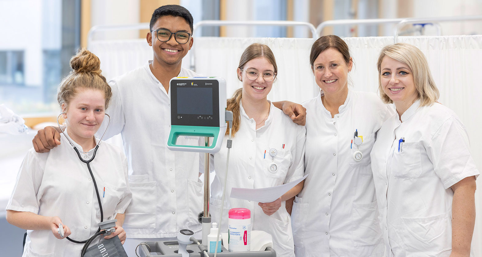 Eine Gruppe von Pflegekräften, die sich umarmt und lächelt | Credit: Markus Rambossek