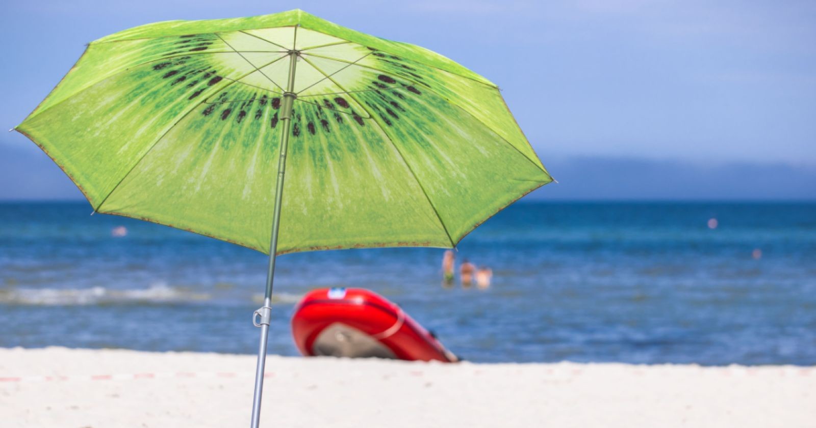 Ein Sonnenschirm am Strand, dahinter das blaue Meer