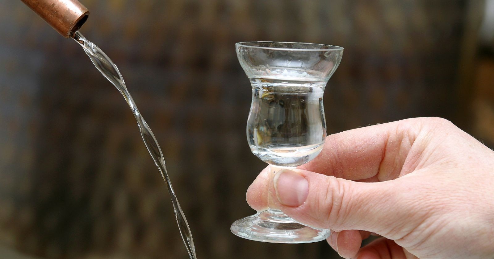 Mann hält ein Schnapsglas in der Hand