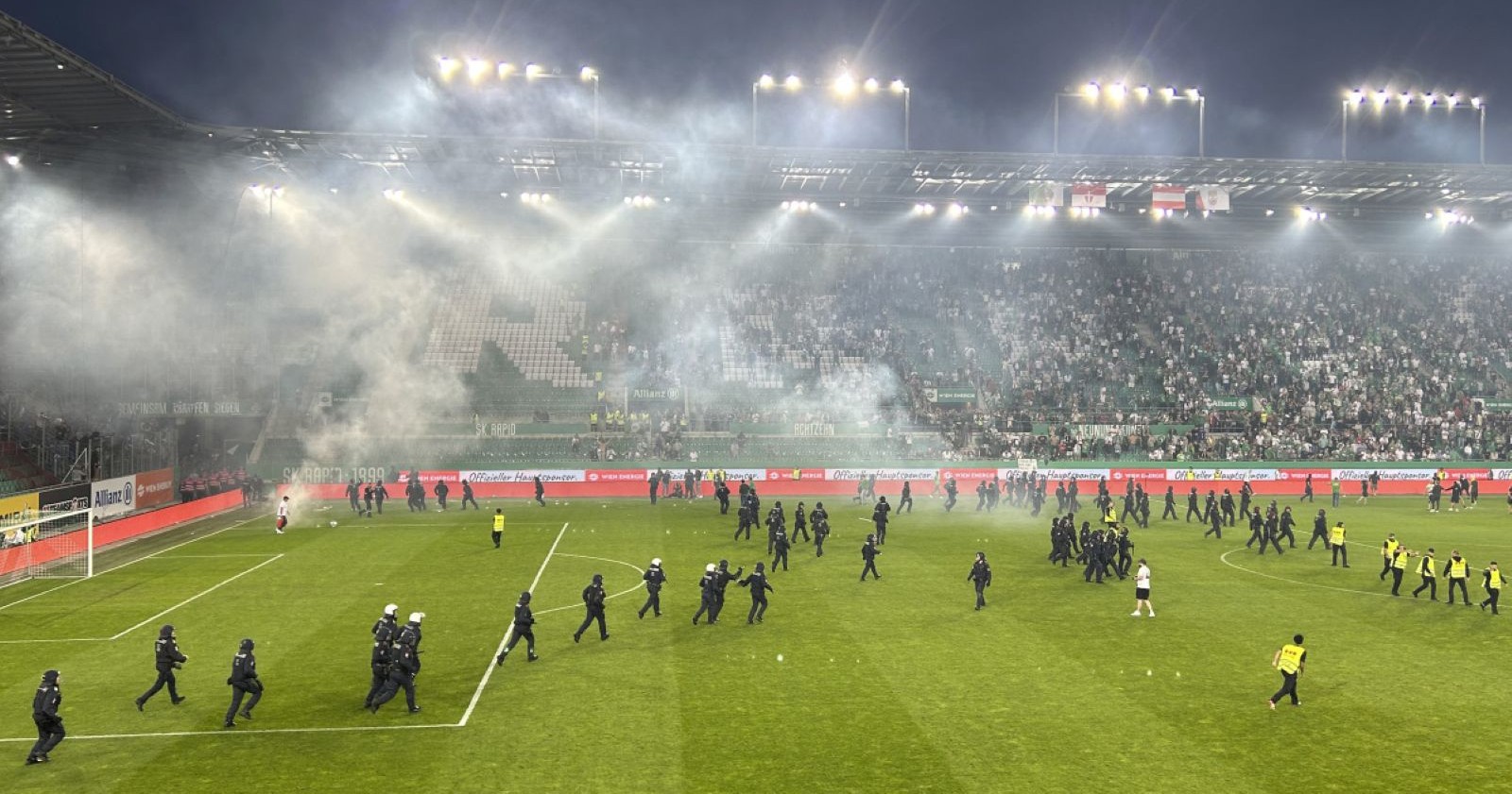 Platzsturm im Wiener Derby 2024 mit Polizei im Einsatz und Rauchentwicklung im Allianz Stadion Wien
