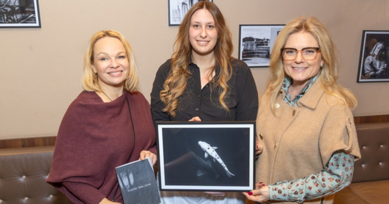 Drei Frauen mit einem Foto der Ausstellung im Café Hummel