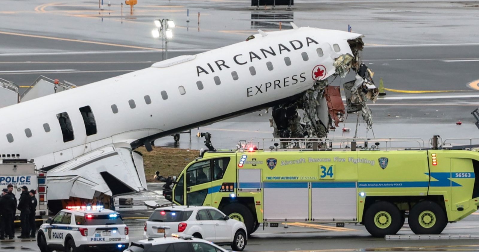 Beschädigte Nase eines Air-Canada-Express-Regionaljets nach Kollision mit einem Flughafen-Feuerwehrauto auf der Landebahn von LaGuardia, Einsatzfahrzeuge und Polizei im Hintergrund