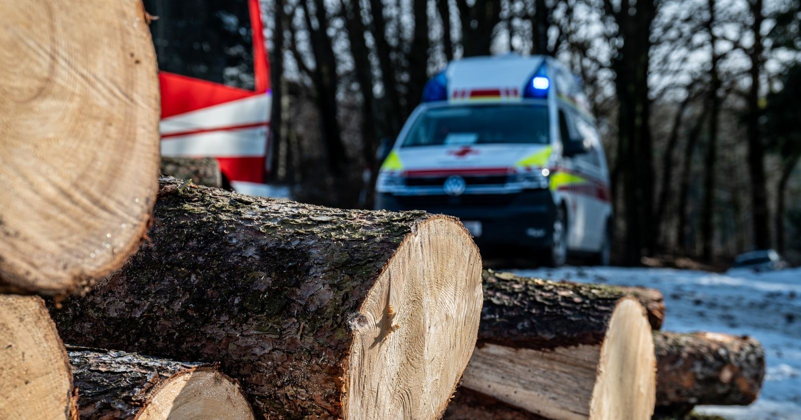 Ein Rettungswagen steht hinter einem Holzstapel
