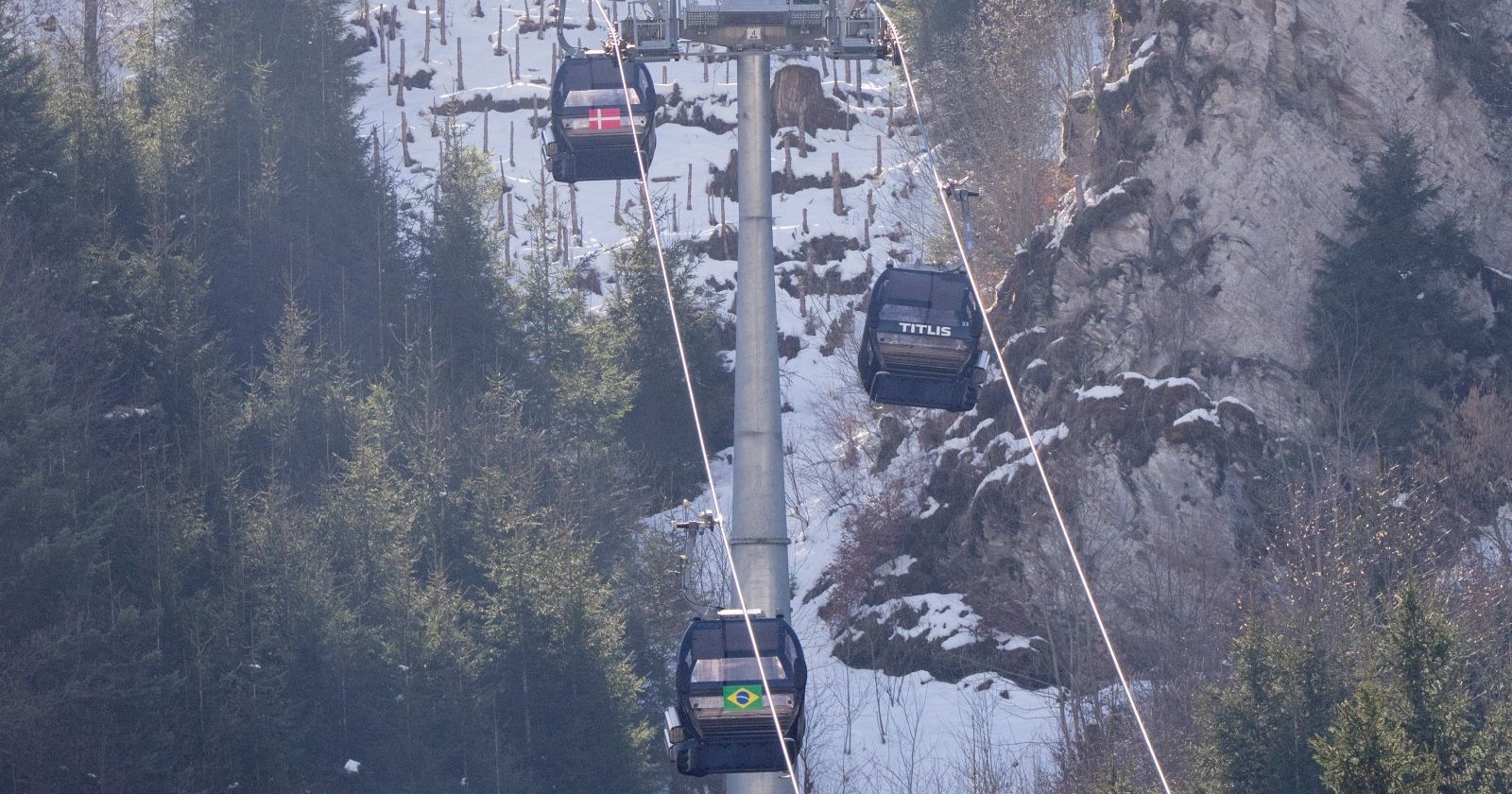 Gondelbahn im Skigebiet Engelberg-Titlis in der Schweiz mit mehreren Kabinen vor verschneitem Berghang