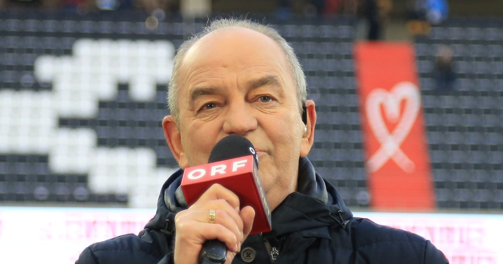Herbert Prohaska als ORF-Experte mit ORF-Mikrofon im Stadion während einer Fußballübertragung