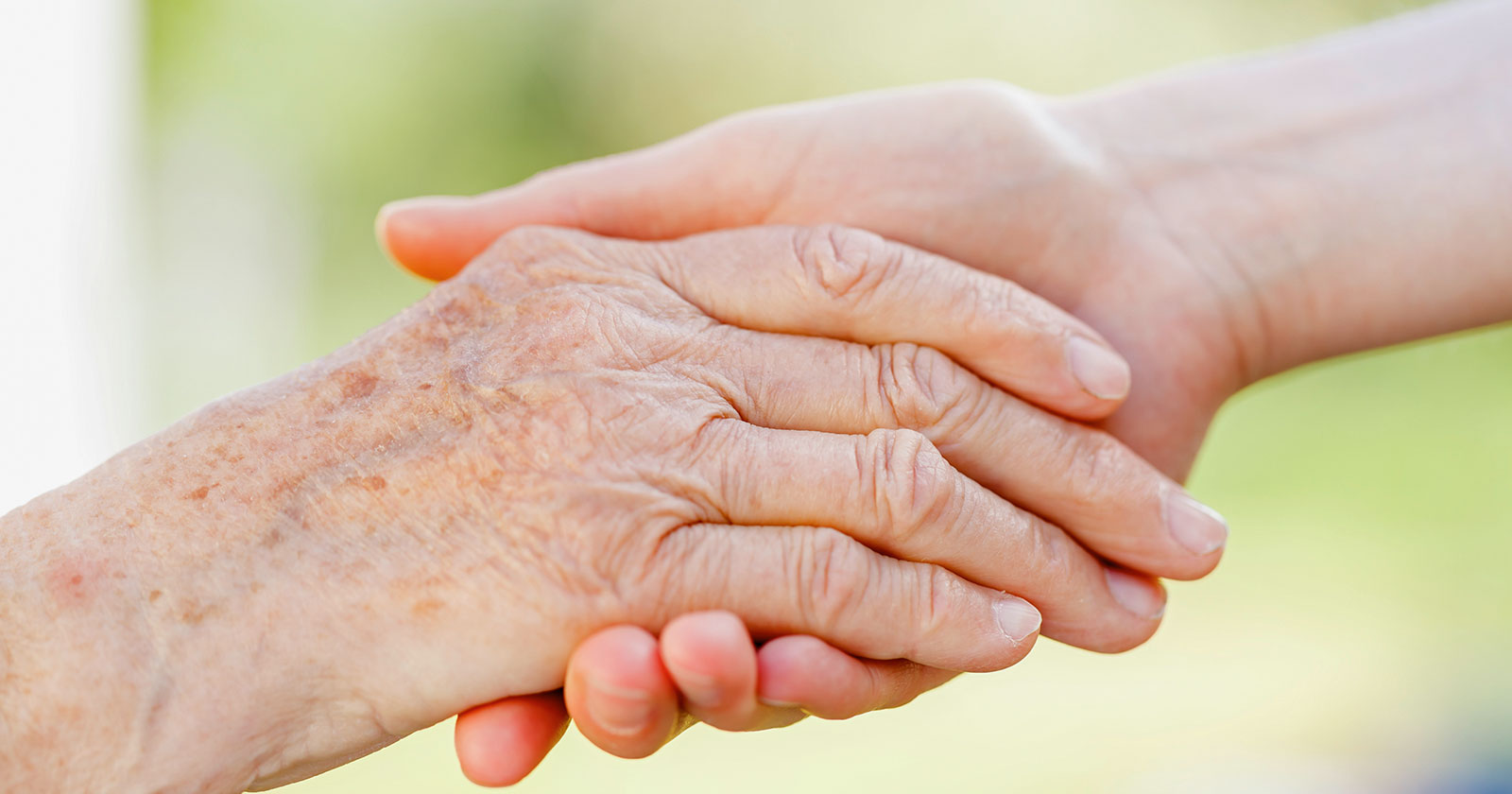 Pflegerin hält die Hand einer Seniorin | Credit: iStock.com/Obencem