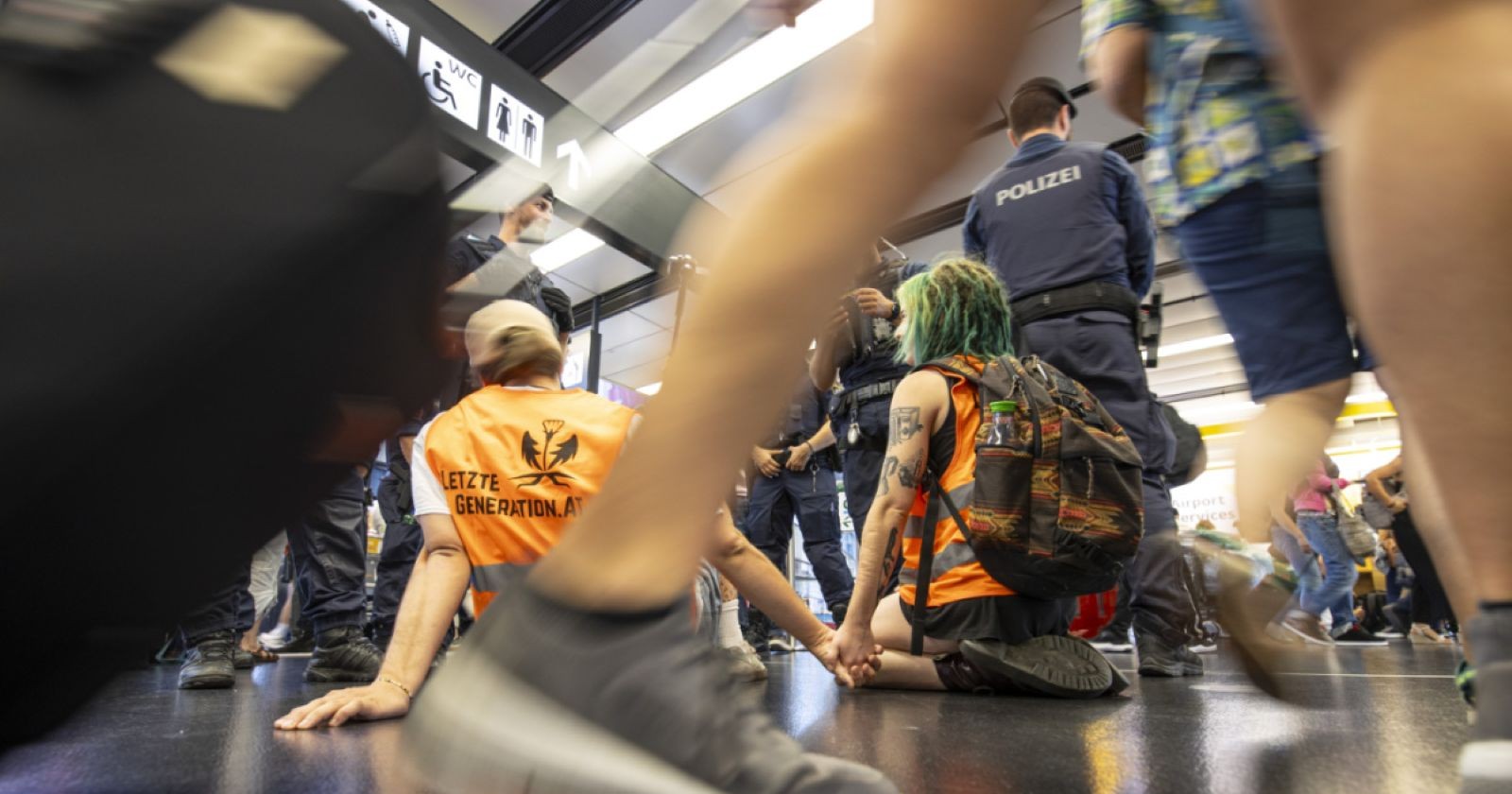 Letzte Generation Aktivisten protestieren am Flughafen Wien-Schwechat und werden von der Polizei abgeführt