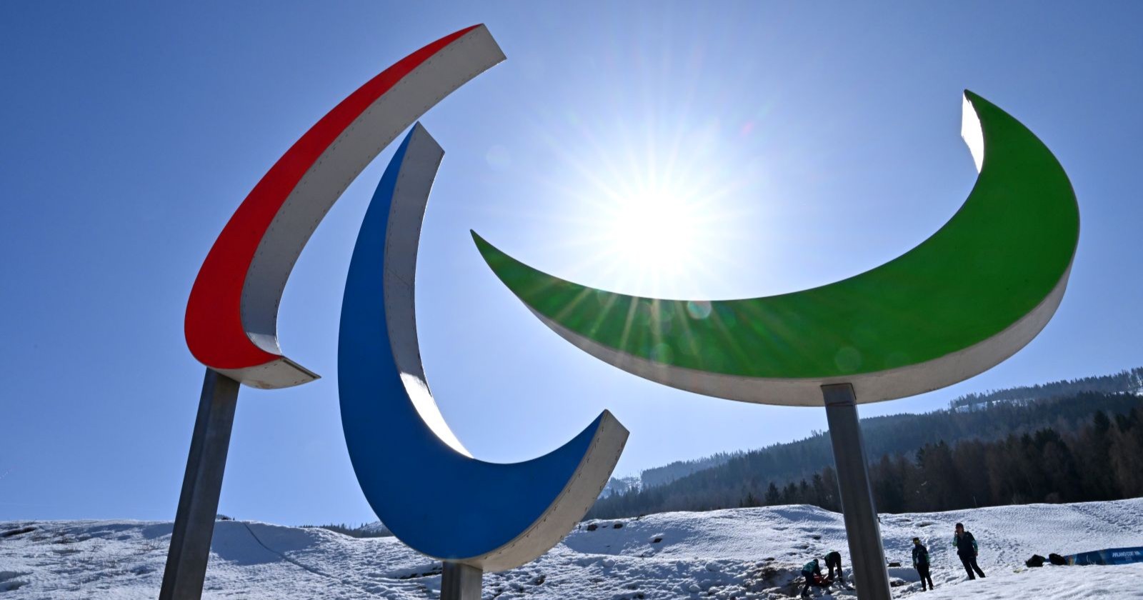 Logo der Paralympischen Winterspiele 2026 vor schneebedeckter Berglandschaft in Cortina d’Ampezzo.
