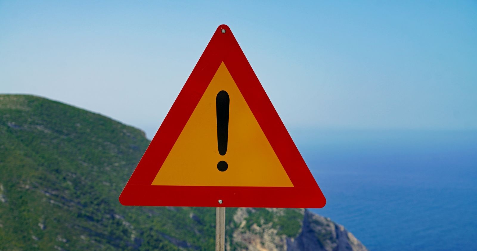 Warnschild vor einer Küste.