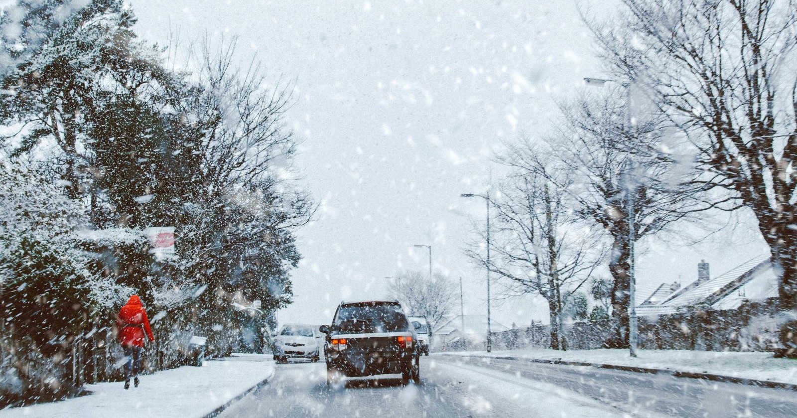 Schnee in Österreich: Winterliches Wetter mit starkem Schneefall auf einer Straße, Autos fahren durch verschneite Landschaft