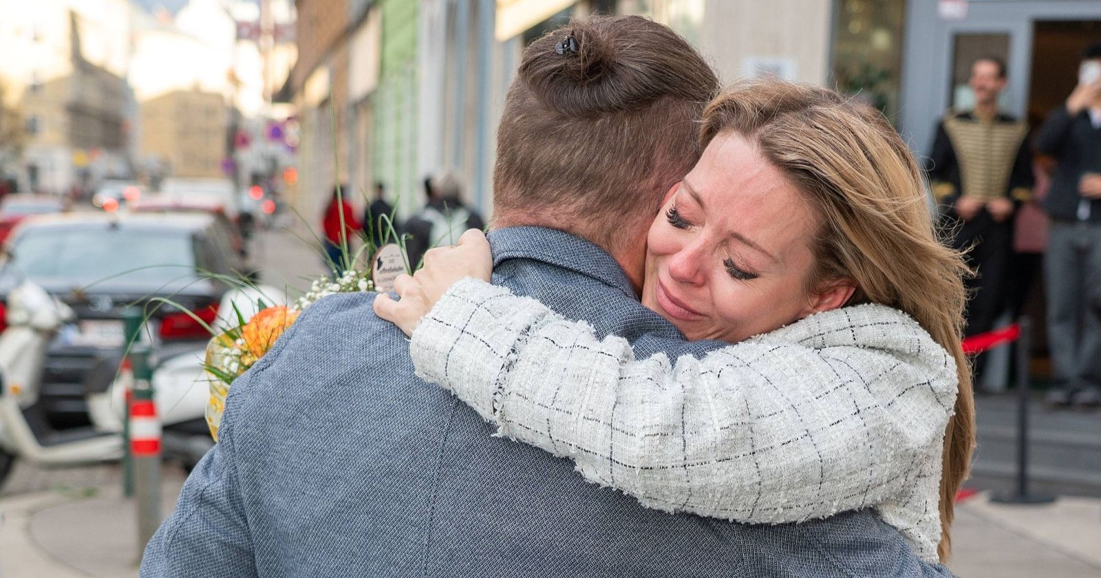 Simone Lugner umarmt einen Mann auf der Straße und wirkt emotional, während sie einen Blumenstrauß erhält/ Emotionale Überraschung: Simone Lugner wird zum Geburtstag mit Blumen im Namen von Richard Lugner überrascht