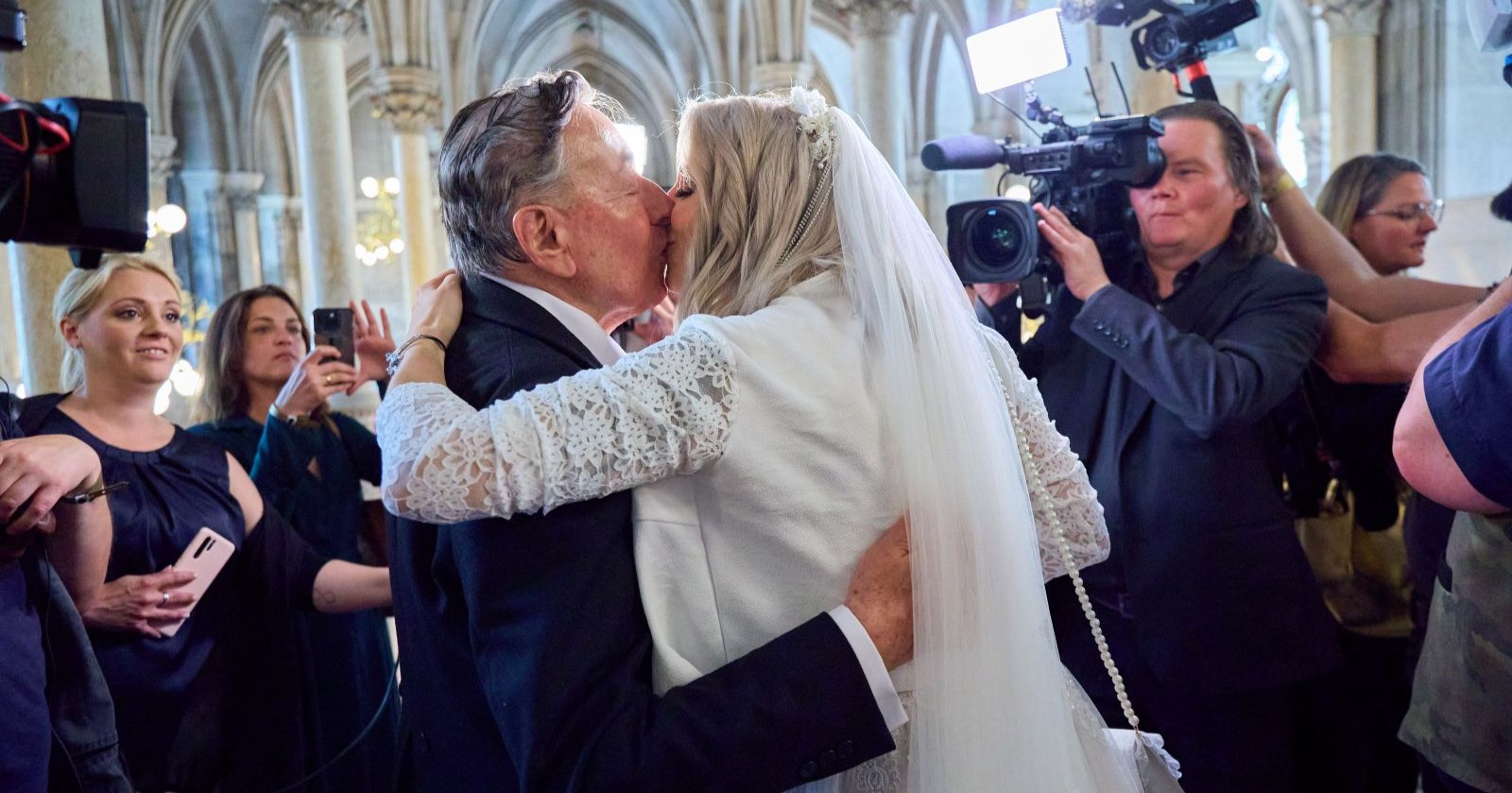 Simone Lugner und Richard Lugner küssen sich bei ihrer Hochzeit im Wiener Rathaus, umgeben von Gästen und Kamerateams
