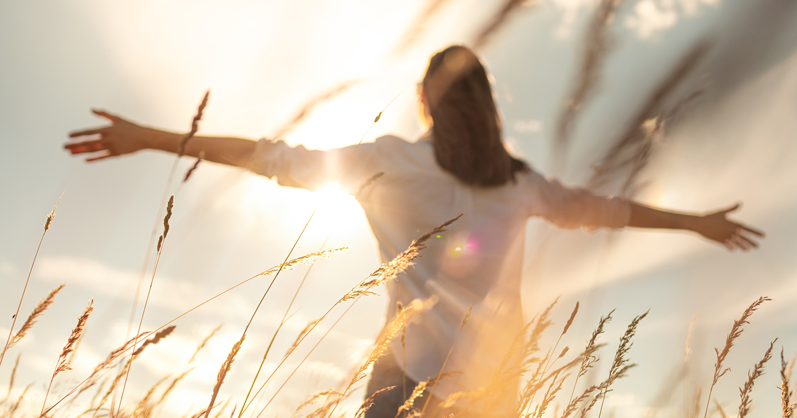 Frau mit weit ausgestreckten Armen im offenen Feld | Credit: iStock.com/kieferpix