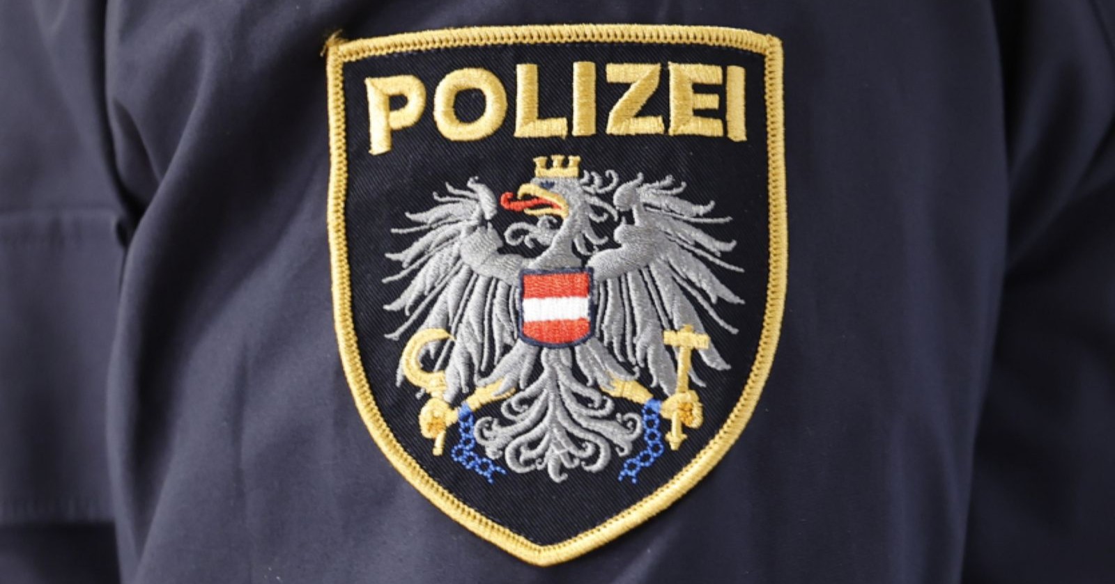 Polizei-Abzeichen mit Bundesadler und Schriftzug „POLIZEI“ auf dunkler Uniform/ Nach der brutalen Home Invasion in Großebersdorf ermittelt die Polizei, drei Verdächtige wurden festgenommen.