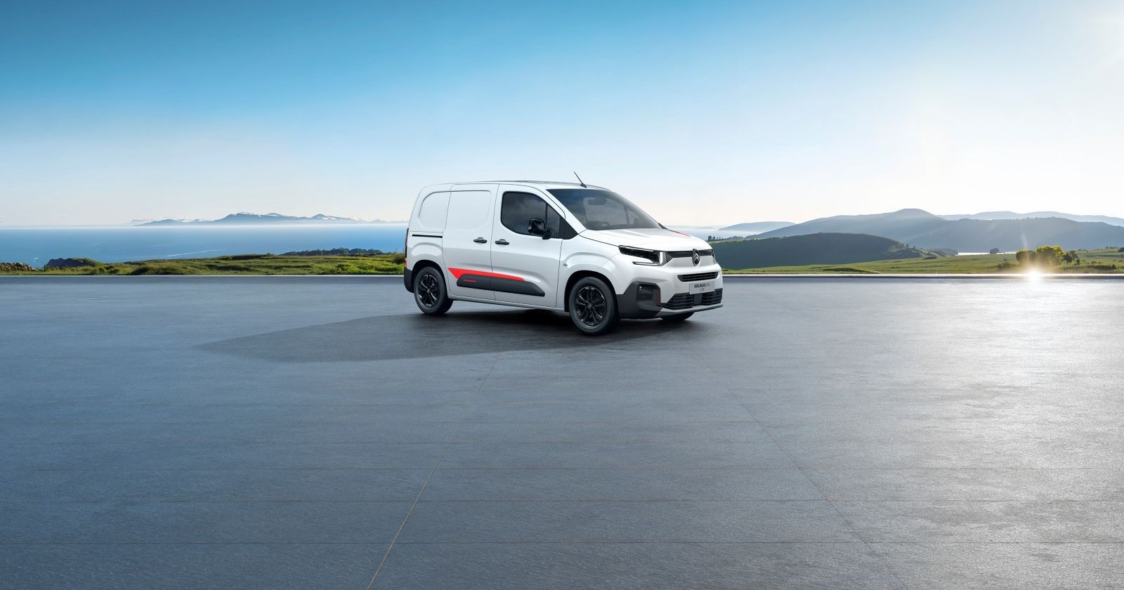 Ein weißer Citroën Berlingo parkt auf einem riesigen Parkplatz. Sonst ist kein Auto zu sehen. Im Hintergrund sind das Meer und einige Inseln zu sehen.