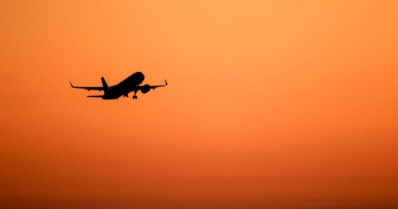 Ein Flugzeug am Himmel bei Abendrot.