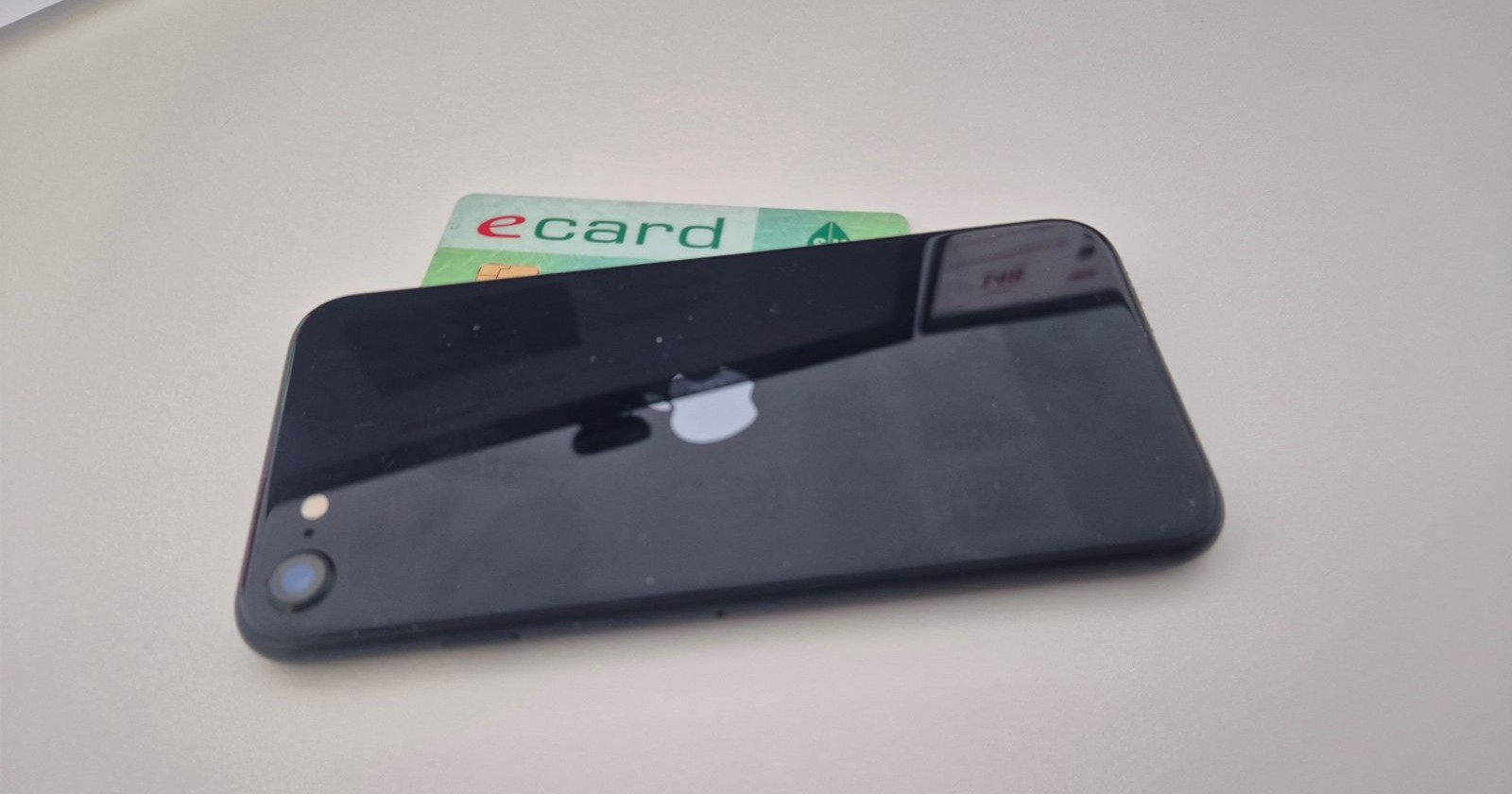 Platzierte physische E-Card unter einem Handy liegend, als Themenbild für die Digitale E-Card am Smartphone