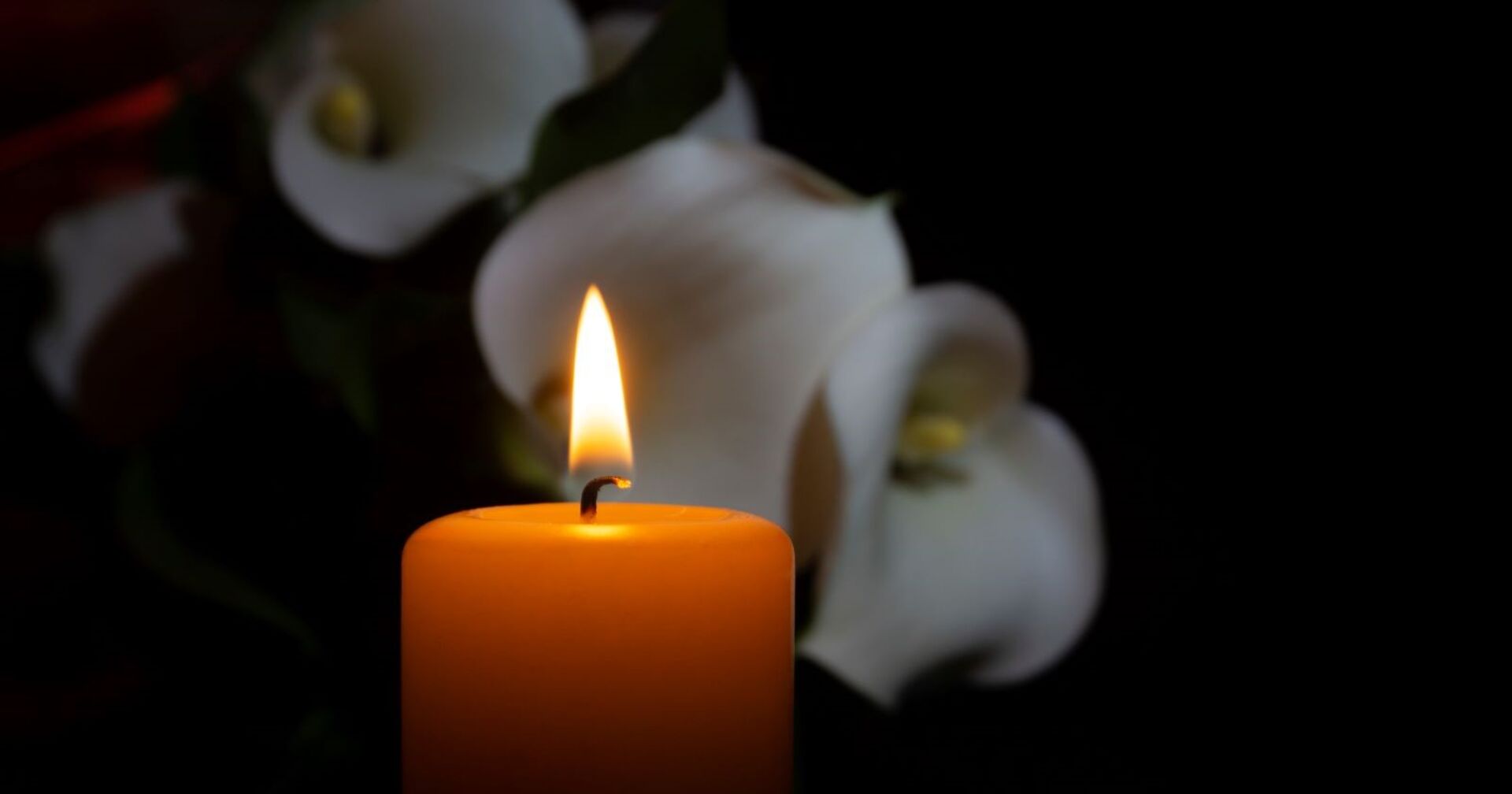 Handball Legende tot: brennende Kerze vor weißen Blumen als Symbol für Trauer um Eduard Korksharov